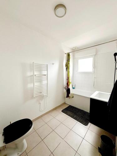 a bathroom with a tub and a toilet and a window at Un calme à la ville in Darnétal