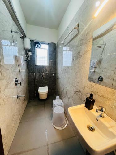 a bathroom with a sink and a toilet and a shower at Anahat Host All 2BHK Service Apartment in Nashik