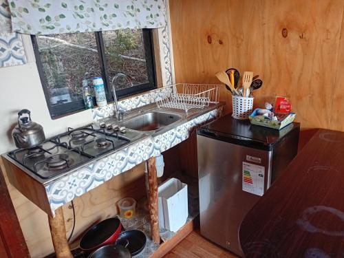 a kitchen with a sink and a stove and a window at Refugio de montaña con vista al mar in Curiñanco