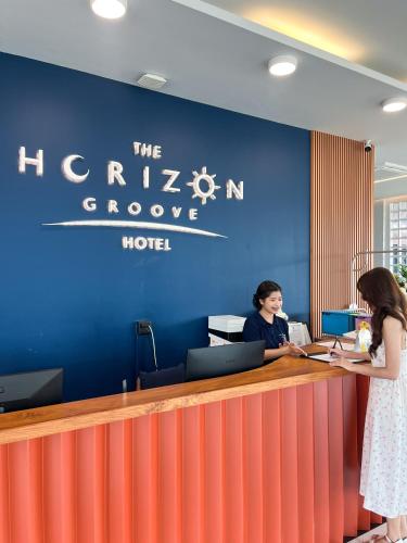 two women standing at a counter in an office at The Horizon Groove Hotel in Ban Khlong