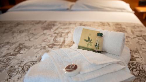 a pile of towels and a bottle of soap on a bed at Tenuta dell'Argento Pool&Relax by Rentbeat in Civitavecchia