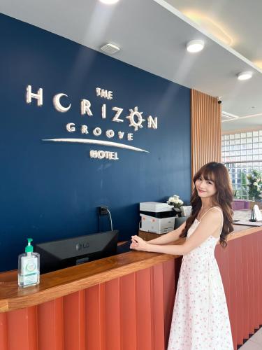 a woman standing in front of a reception desk at The Horizon Groove Hotel in Ban Khlong