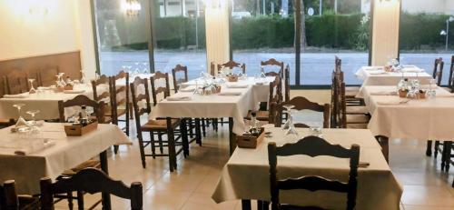 a dining room with tables and chairs with white tablecloths at Hostal Restaurant Sant Marçal in Amer
