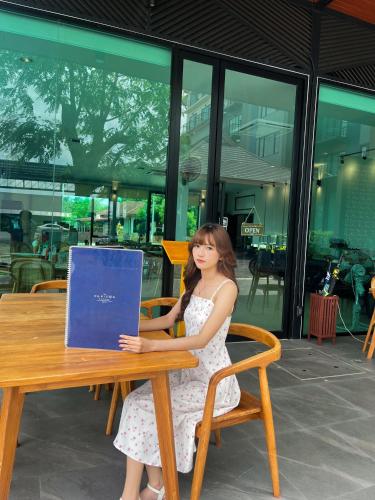 a young woman sitting at a table with a laptop at The Horizon Groove Hotel in Ban Khlong