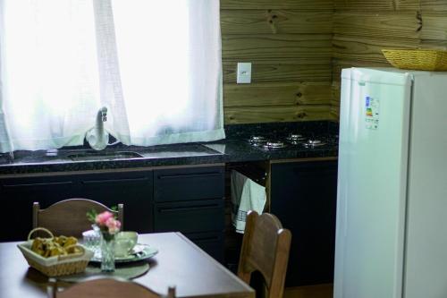 a kitchen with a table and a white refrigerator at Chalet in Bom Princípio in Bom Princípio