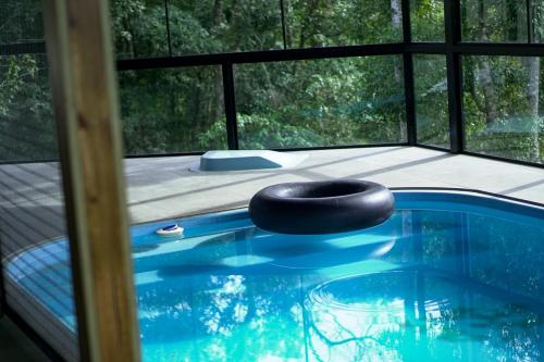 a swimming pool with a black oar in front of a window at Chalet in Bom Princípio in Bom Princípio