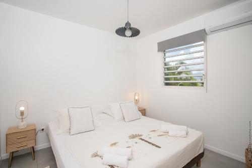 レ・トロワ・イレにあるVilla Hateya, vue mer et piscine privéeのベッドと窓のある白い寝室