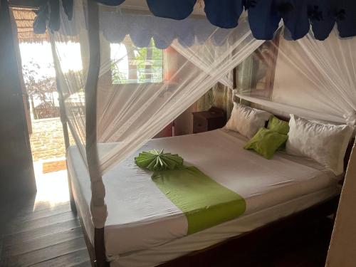 a bedroom with a white canopy bed with green pillows at Villa Maroloko in Ifaty