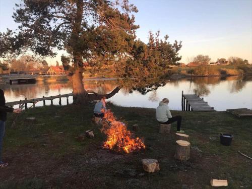 two people sitting around a campfire next to a lake at 30189-Malling-Fjordvej-52 in Malling