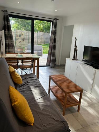 a living room with a couch and a tv and a table at Le Lotus Oasis des Pins avec piscine in Labenne