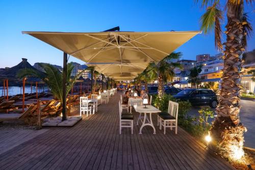 a restaurant with tables and chairs under a large umbrella at Sunset Aparthotel in Sarandë