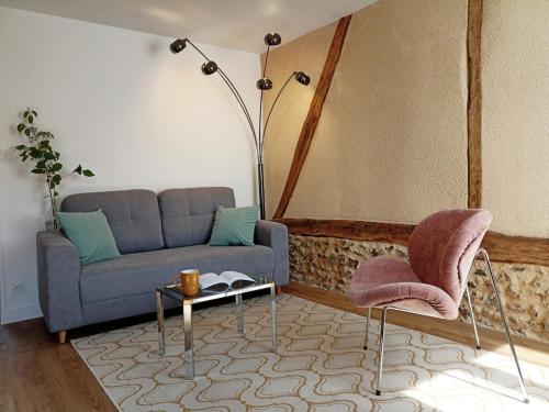 un soggiorno con un divano, un tavolo e delle sedie di Maisonnette en centre ville a Breteuil-sur-Iton