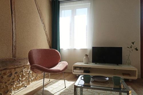 a living room with a chair and a television at Calme petite maison normande au coeur de Breteuil in Breteuil-sur-Iton
