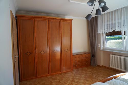 a bedroom with a large wooden cabinet and a window at Panorama Appartements in Itter