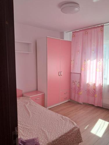 a bedroom with a pink cabinet and a bed at Adrian in Piteşti