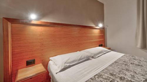 a bed with a wooden headboard in a bedroom at Tenuta dell'Argento Pool&Relax by Rentbeat in Civitavecchia