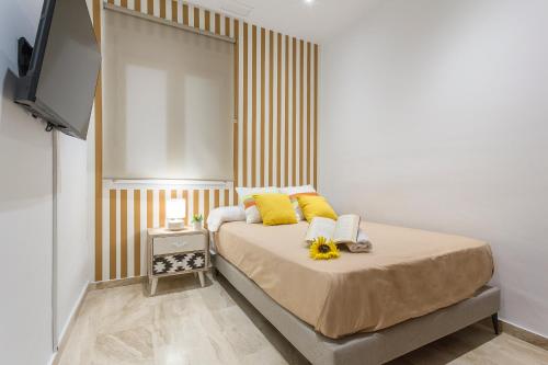 a bedroom with a bed with yellow pillows and a television at Cadiz Playa 3 Rooms in Cádiz
