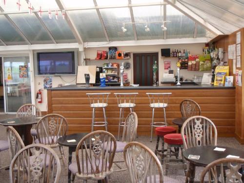 a restaurant with tables and chairs and a bar at Chalets & Lodges at Atlantic Bays Holiday Park in Padstow