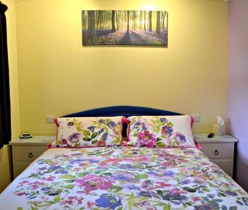 a bedroom with a bed with a floral bedspread at Little Bullocks Farm in Takeley