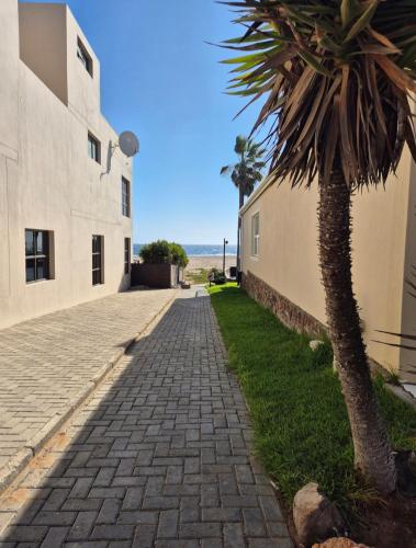 a cobblestone street next to a building with a palm tree at PhilCo Seaside Self Catering in Langstrand