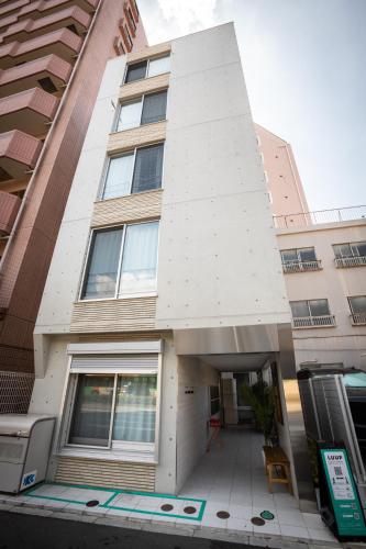 aartment building with a white facade and a door at Mi-HOTEL KAGURAZAKA in Tokyo