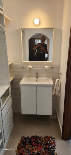 a man taking a picture of a bathroom with a sink at Kamuli Cottage in Entebbe
