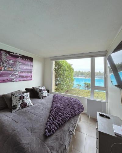 a bedroom with a large window with a large bed at Depto Frente a Laguna y Patio Privado in San Antonio