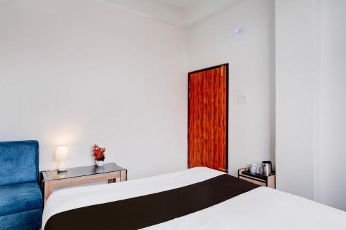 a bedroom with a bed and a blue chair at Hotel O Aradhyaa Inn in Dispur