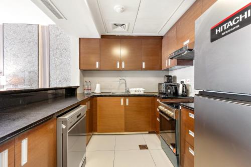 a kitchen with wooden cabinets and stainless steel appliances at Desert Key - Platinum Apartments in Gate Tower, Al Reem Island in Abu Dhabi