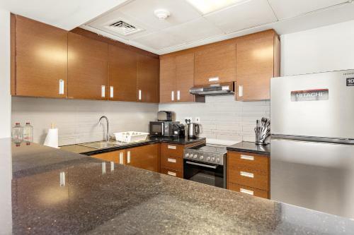 a kitchen with wooden cabinets and a stainless steel refrigerator at Desert Key - Platinum Apartments in Gate Tower, Al Reem Island in Abu Dhabi
