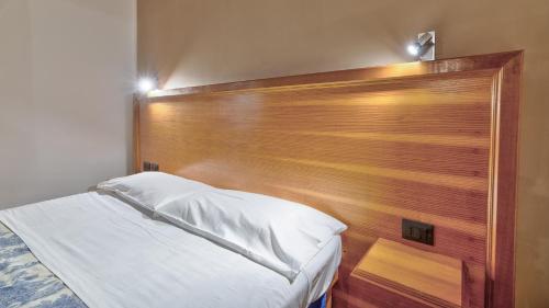 a bed with a wooden headboard in a bedroom at Tenuta dell'Argento Pool&Relax by Rentbeat in Civitavecchia