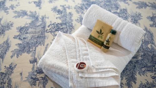 a white towel with a bottle of alcohol and a book at Tenuta dell'Argento Pool&Relax by Rentbeat in Civitavecchia
