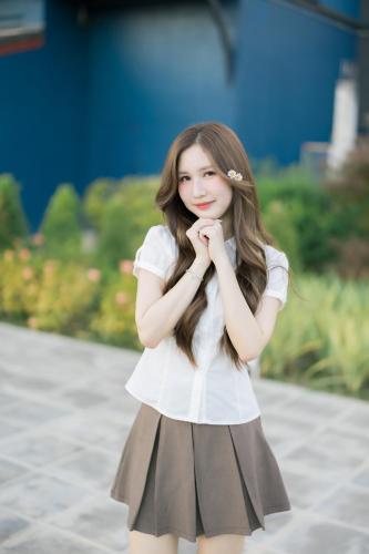a young girl wearing a white shirt and a skirt at The Horizon Groove Hotel in Ban Khlong