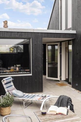 a house with a chair and a book on a patio at 30467-Odder-Ravnsager-15 in Odder