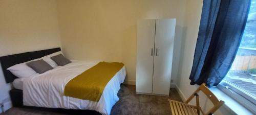 a bedroom with a bed and a cabinet and a window at JosteeStay Apartments - London Rooms E6 2AU in London