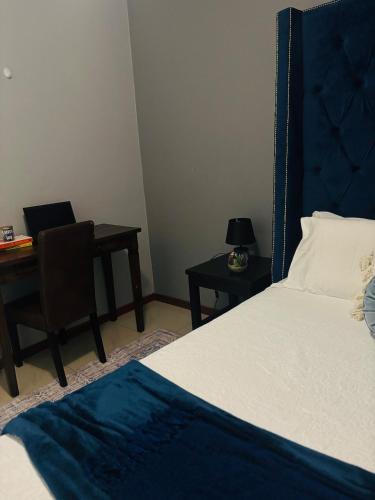 a bedroom with a bed and a desk with a laptop at Tubungu- House of Lux& Lush in Matsapha