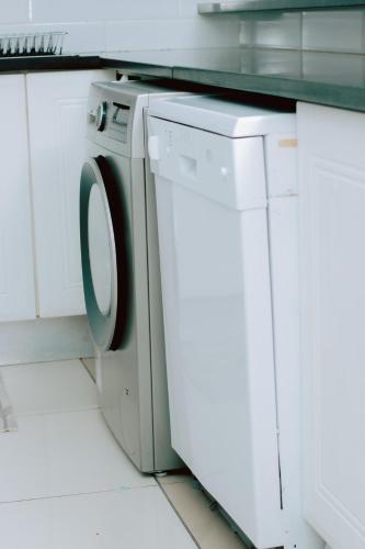a washing machine in a white laundry room at Tubungu- House of Lux& Lush in Matsapha