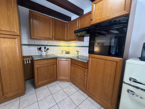 a small kitchen with wooden cabinets and a sink at Relais du Dompeter in Molsheim