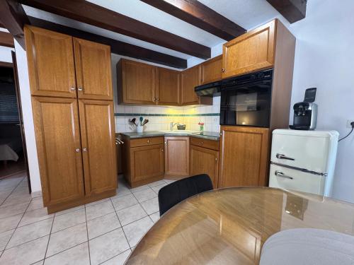 a kitchen with wooden cabinets and a table in it at Relais du Dompeter in Molsheim