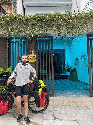 a man standing in front of a house with a bike at Muong Thanh Homestay in Diện Biên Phủ