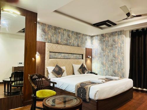 a bedroom with a bed and a chair and a table at Trimrooms Triumph Banaras Railway Station in Varanasi