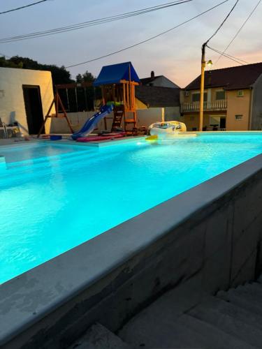 a swimming pool with a playground in the background at Apartments Lana in Mostar