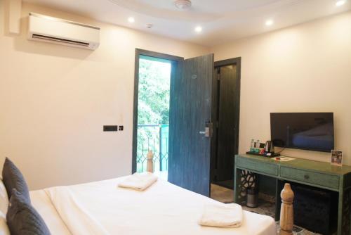a bedroom with a bed and a television and a desk at Baga Courtyard in Anjuna