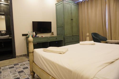 a bedroom with a bed and a dresser with a television at Baga Courtyard in Anjuna