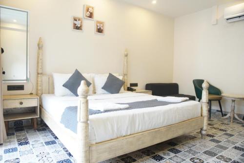 a bedroom with a large white bed and a mirror at Baga Courtyard in Anjuna