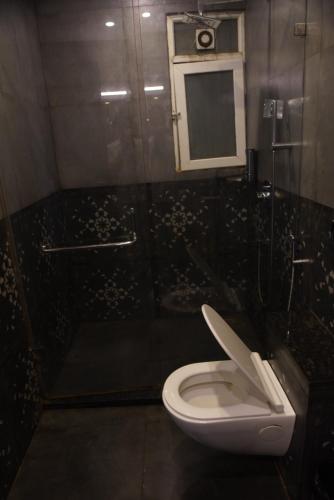 a bathroom with a toilet and a shower and a mirror at Baga Courtyard in Anjuna