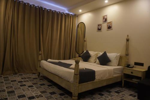 a bedroom with a bed with a mirror and curtains at Baga Courtyard in Anjuna