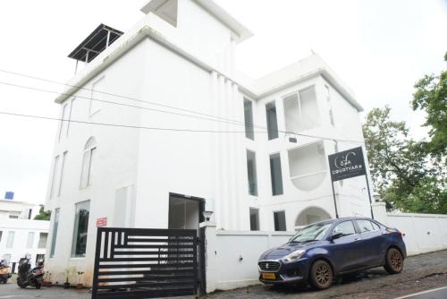 a blue car parked in front of a white house at Baga Courtyard in Anjuna