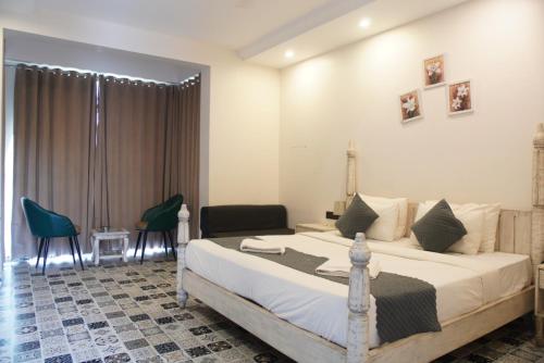 a bedroom with a bed and chairs in a room at Baga Courtyard in Anjuna