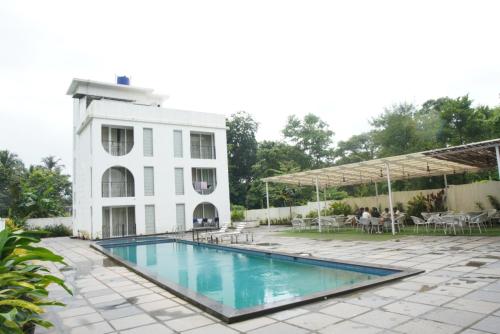 a swimming pool in front of a white building at Baga Courtyard in Anjuna